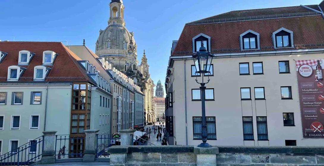 Una encantadora calle en Dresde, Alemania, con la cúpula de la Frauenkirche al fondo.