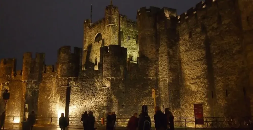 Turyści podziwiają zamek Gravensteen w Gandawie nocą.