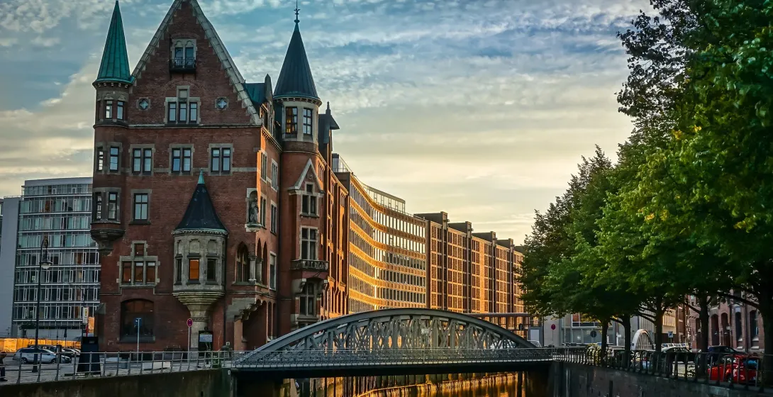 Vista al atardecer de un encantador canal en Hamburgo, Alemania, con un singular edificio de ladrillo y un puente.
