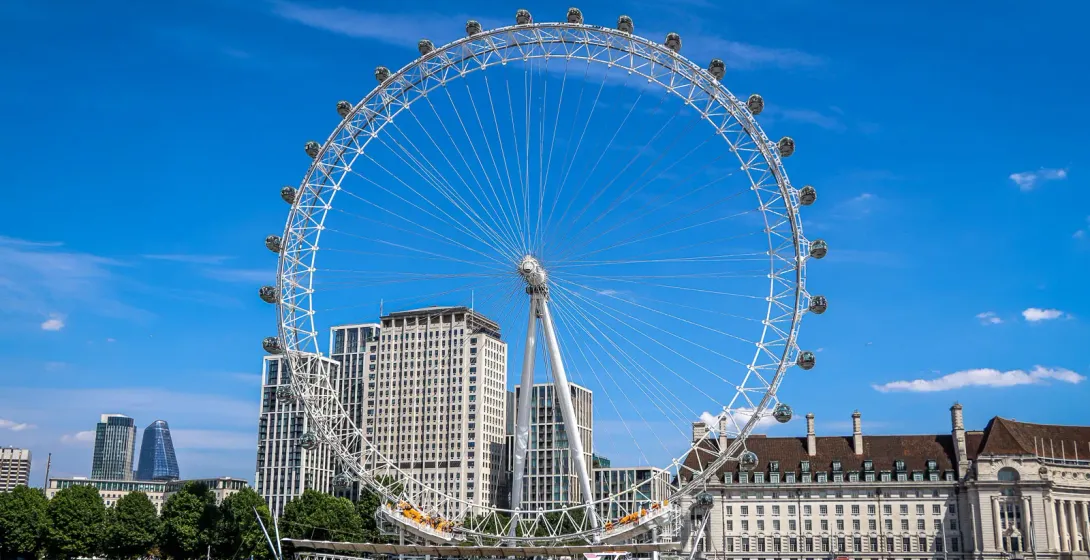 London Eye wznosi się wysoko na tle bezchmurnego, niebieskiego nieba.