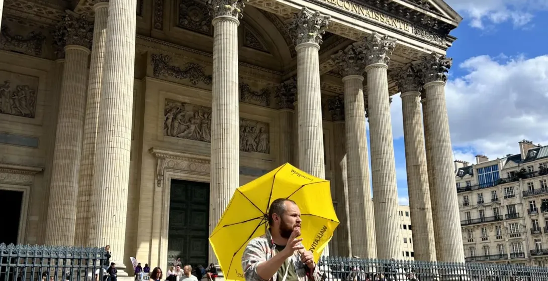 Un guía turístico dirige un grupo por el Barrio Latino de París, mostrando el Panteón.