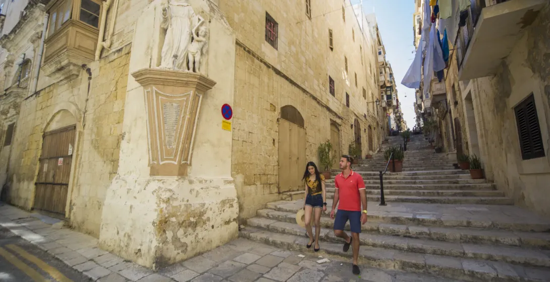 Una pareja sube una escalera histórica en La Valeta, Malta.