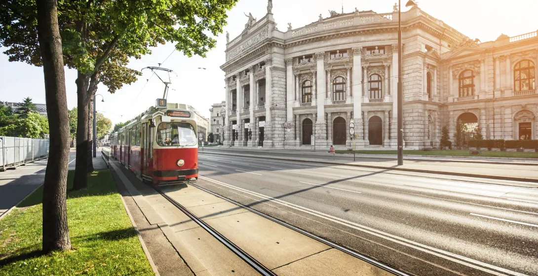 Czerwony tramwaj jedzie obok Wiedeńskiej Opery Państwowej.