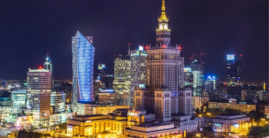 Nocna panorama Warszawy z charakterystycznymi budynkami.