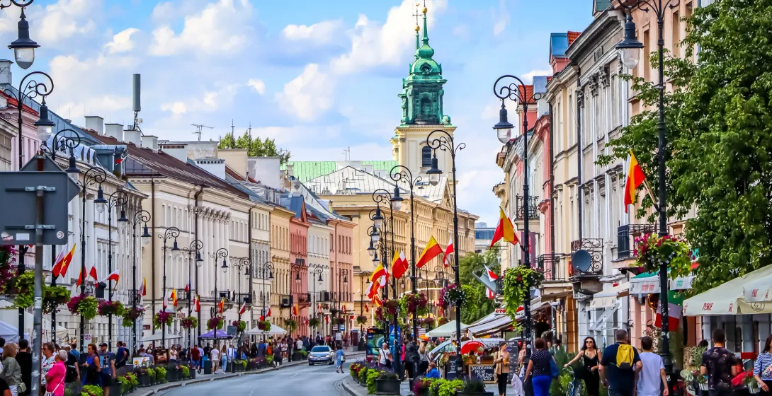 Żywa ulica w Warszawie, Polska, z kolorowymi budynkami i wieloma ludźmi.