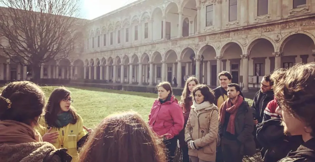Tour guide speaking to a group of visitors in a historic colonnaded courtyard.