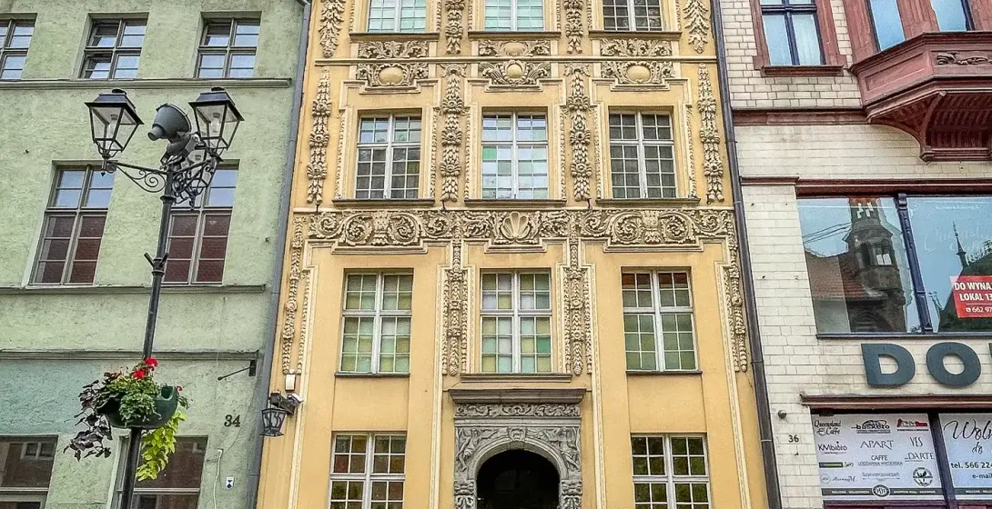 A row of historic buildings in Gdansk, Poland, featuring ornate facades and European architecture under a bright sky.