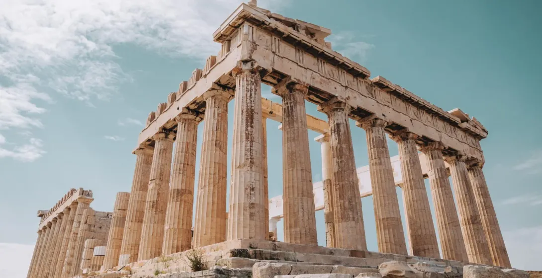 Vista del templo Partenón en la Acrópolis de Atenas, mostrando columnas dóricas bajo un cielo parcialmente nublado.