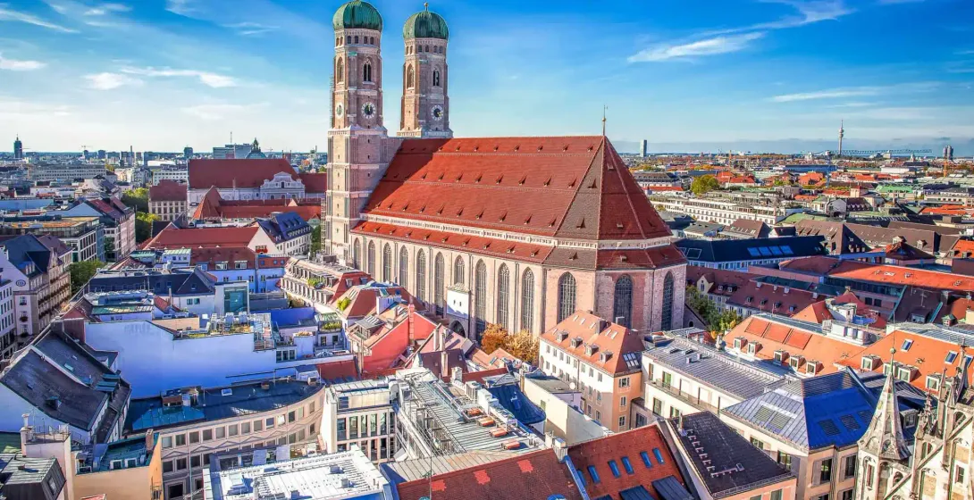 Aerial view of Munich's Frauenkirche (Cathedral of Our Blessed Lady) with its twin green domed towers, surrounded by city roo