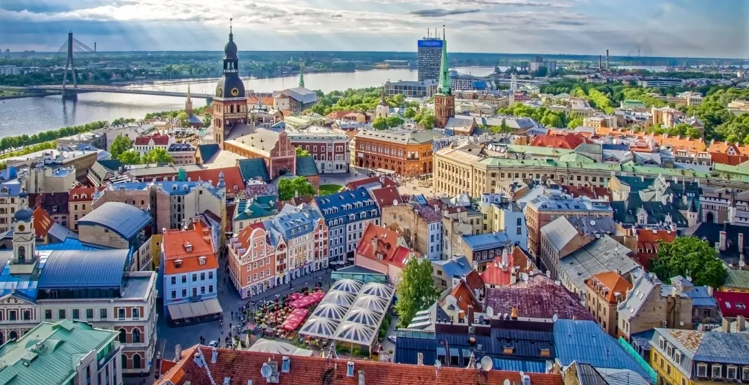 Panoramic aerial view of Riga Old Town with colorful rooftops, historic churches, and the Daugava River.