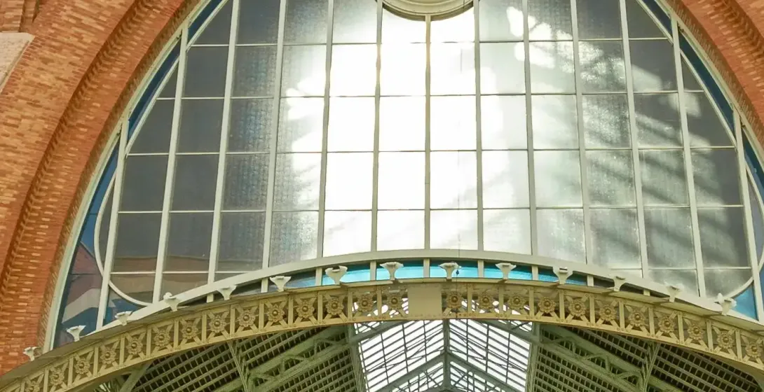 Fachada del Mercado Central de Valencia, con ladrillo, un gran ventanal arqueado, un escudo y estructura de techo de metal ve