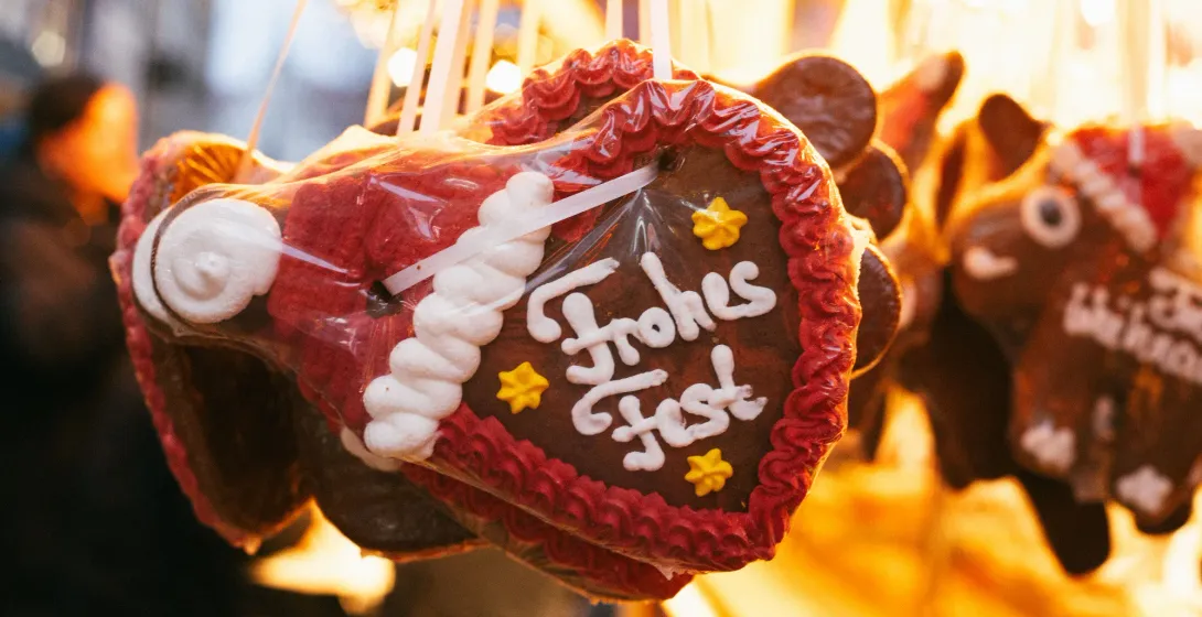 Verziertes Lebkuchenherz mit der Aufschrift „Frohes Fest“ an einem Weihnachtsmarktstand.