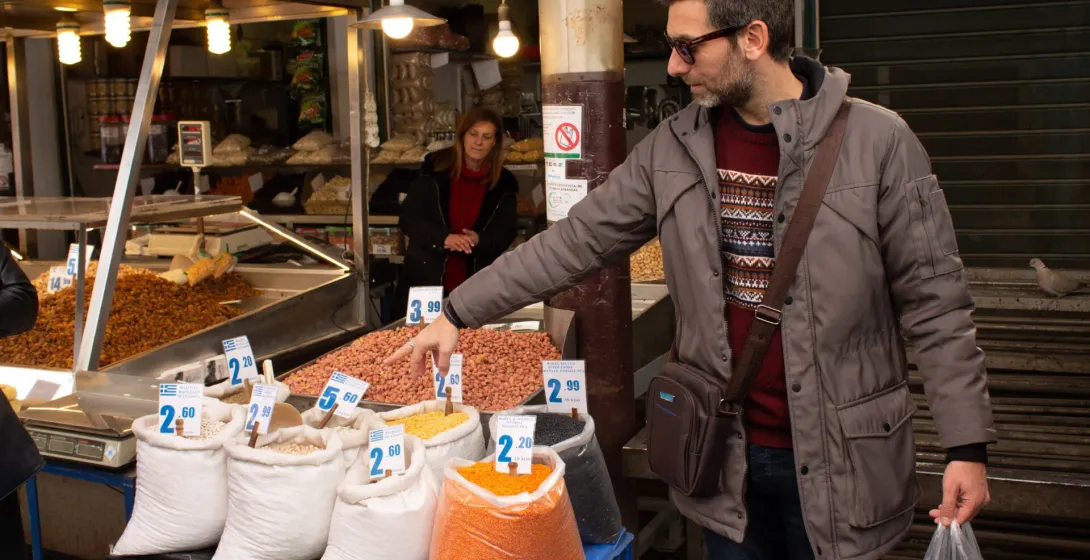 Un guía turístico muestra a los turistas varias legumbres y frutos secos en un vibrante mercado de Atenas, Grecia.