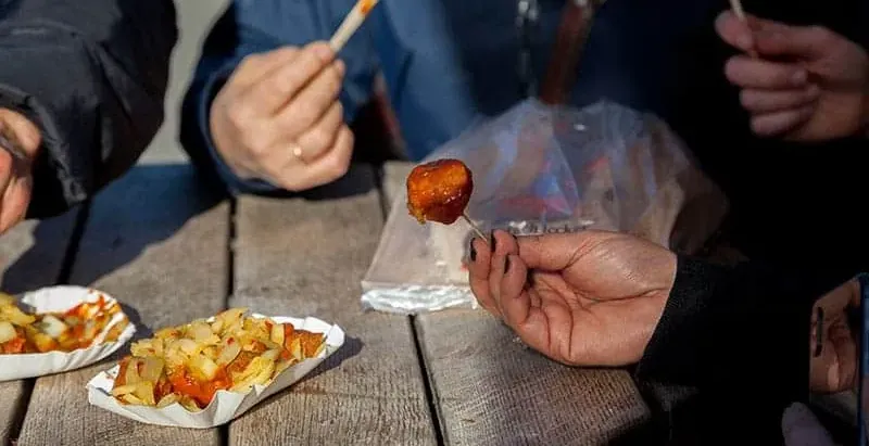 Turyści jedzą Currywurst w Berlinie.