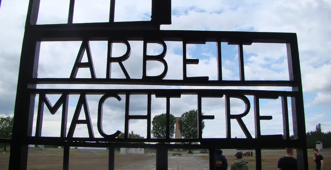 Turyści odwiedzający bramę obozu koncentracyjnego Sachsenhausen w Berlinie, Niemcy.