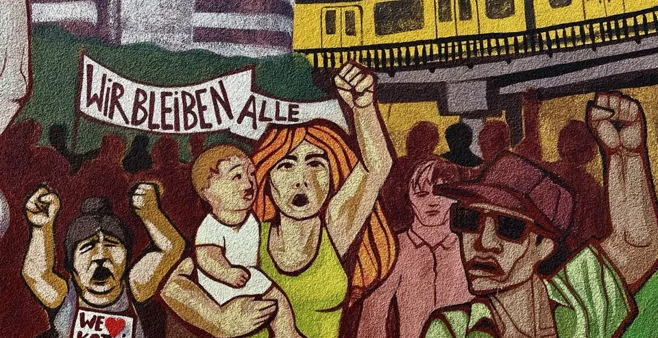 Żywy mural w Berlinie przedstawiający scenę protestu z różnymi ludźmi i pociągiem metra.