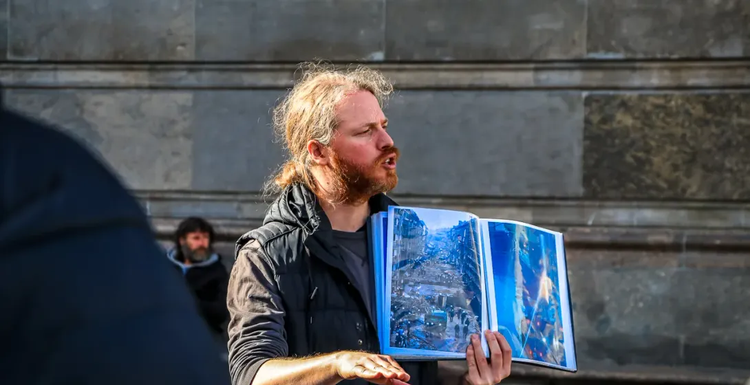 A tour guide in Berlin shows photos to a small group.