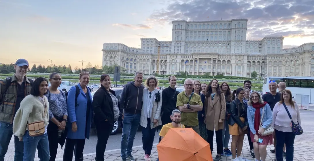 Un gran grupo de turistas disfruta de una visita guiada por Bucarest, posando frente al impresionante Palacio del Parlamento.