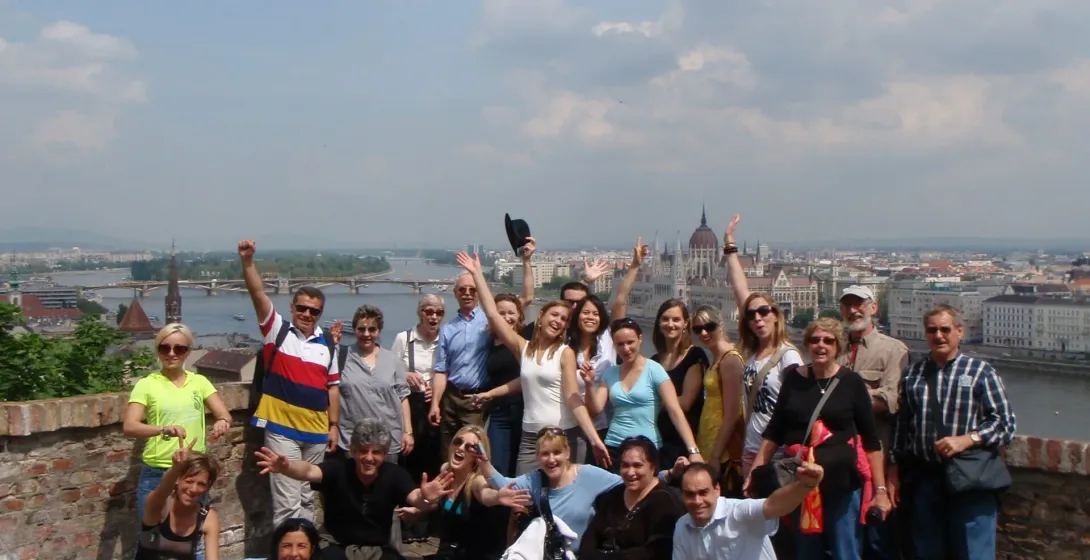 Happy tour group in Budapest, Hungary, with the Parliament Building in the background.