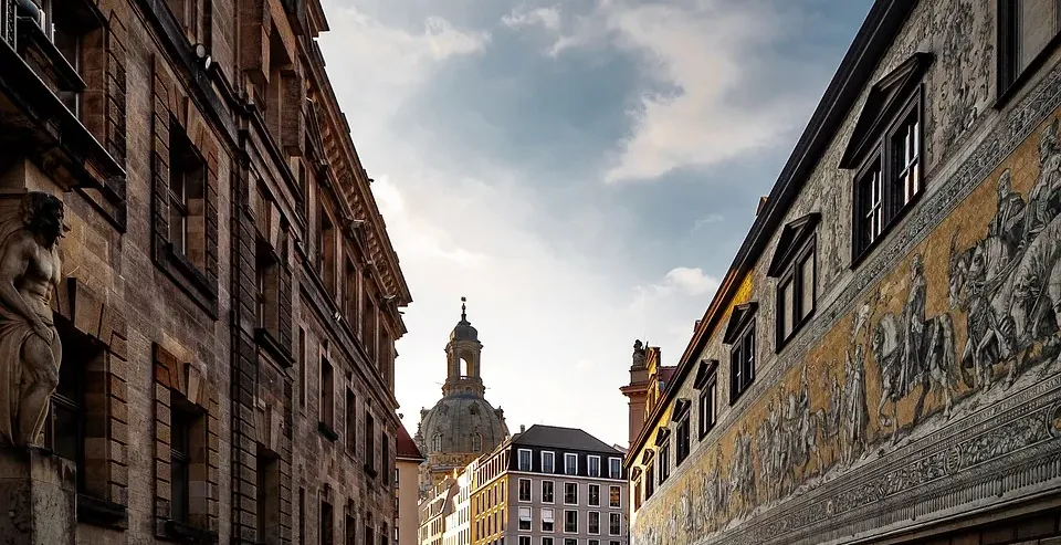 Calle empedrada en Dresde, Alemania, con edificios históricos y un fresco.