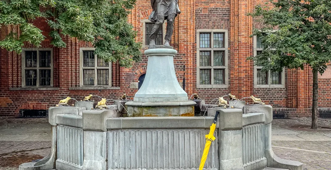 Bronze violinist statue on a fountain in Gdansk's historic square.