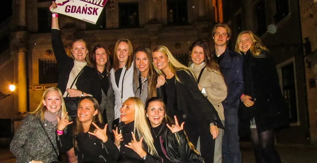 Wesołe turystki i turyści na pub crawl w Gdańsku.