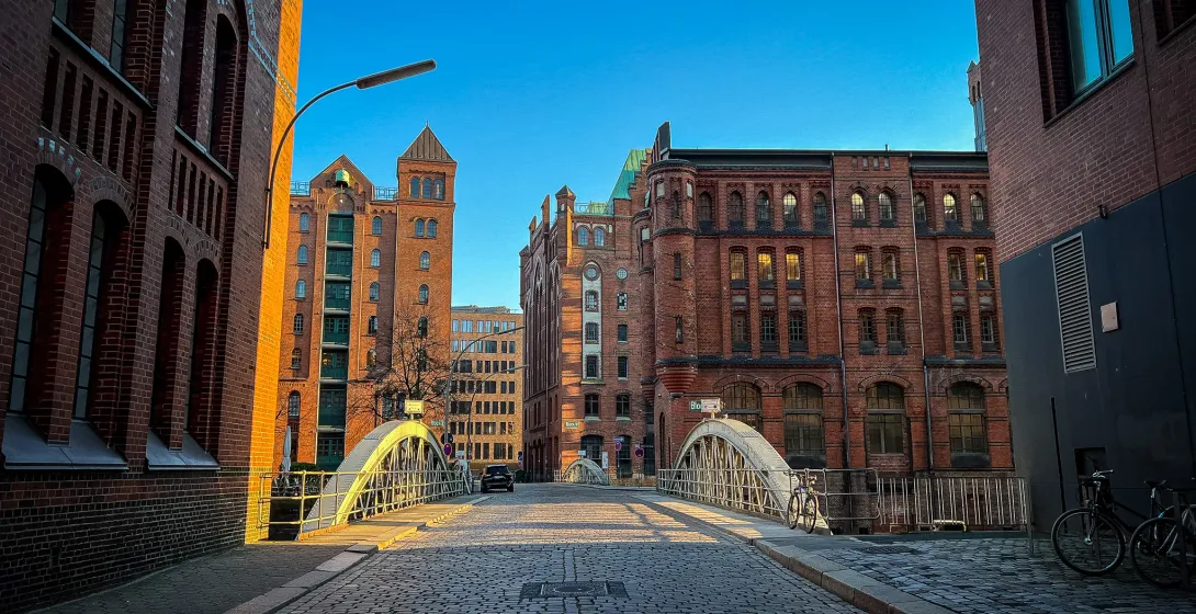 Calle empedrada en Hamburgo, Alemania, que conduce a un puente con edificios históricos de ladrillo.