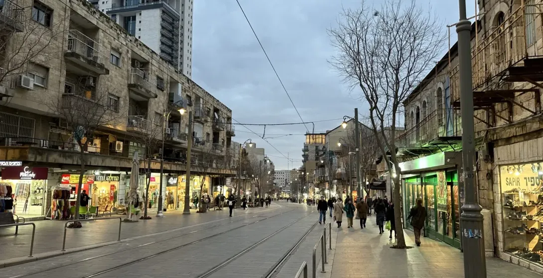 Abendblick auf eine Fußgängerzone in Jerusalem mit Geschäften und Fußgängern.