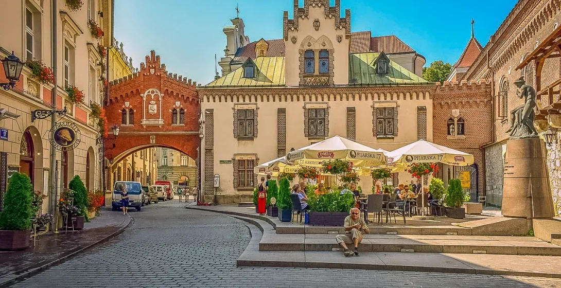 Charming Krakow street scene with Floriańska Gate and outdoor cafe.