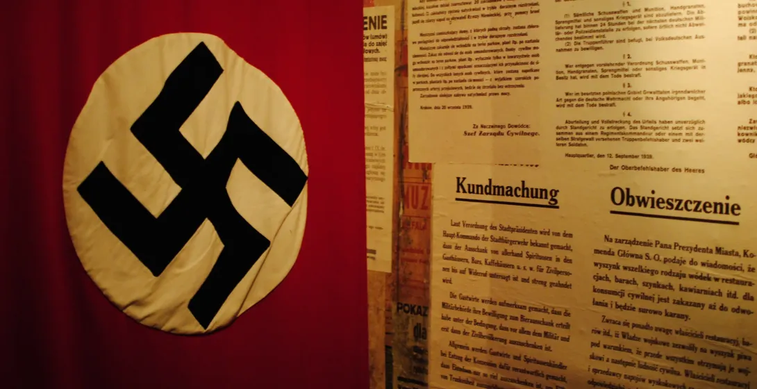 Close-up of a Nazi swastika flag and historical posters in a museum.