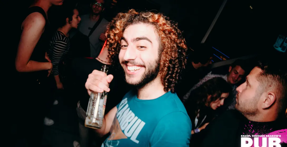 Uśmiechnięty mężczyzna bawi się na pub crawl w Krakowie, Polska.