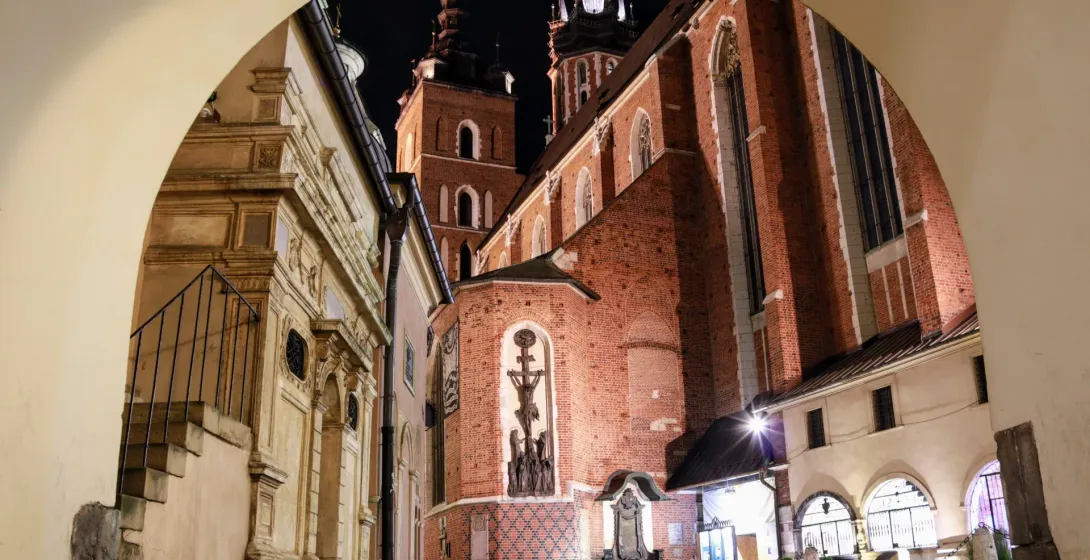 La Basílica de Santa María en Cracovia de noche, vista a través de un arco.