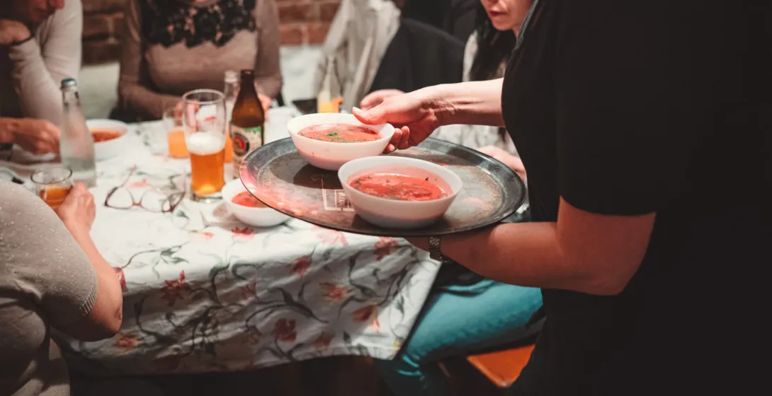A server brings delicious borscht soup to a group enjoying a food tour in Krakow.
