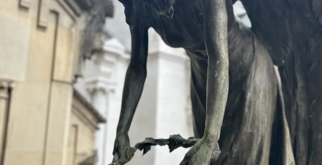 Una escultura de bronce de un ángel en el cementerio Rakowicki de Cracovia, colocando una corona de flores sobre una figura.