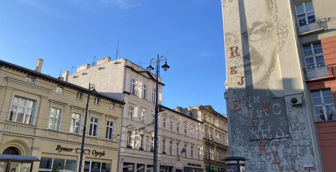 Słoneczna scena uliczna w Krakowie, Polska, z dużym muralem.