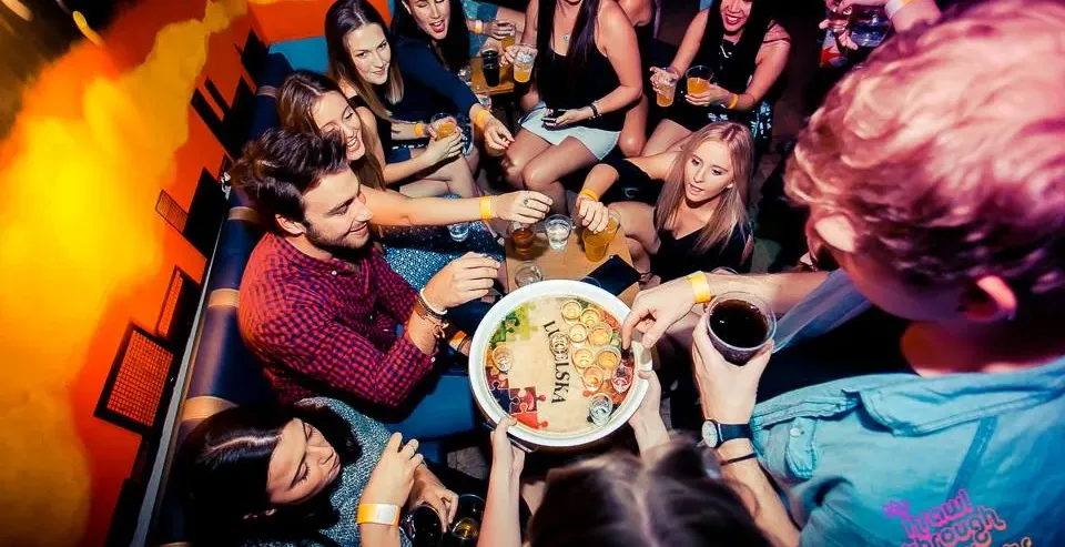 Grupa przyjaciół bawi się na pub crawl w Krakowie.