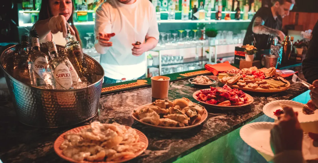 Guests enjoying a Polish food tour in Krakow, sampling pierogi and other local delicacies at a bar.