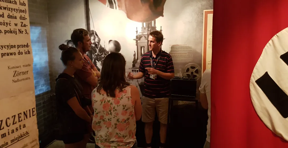 Un grupo de turistas en una visita guiada a un museo de Cracovia, aprendiendo sobre historia.