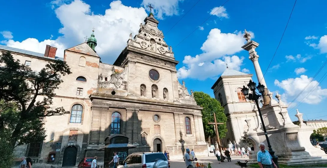 Turyści zwiedzający historyczną bazylikę św. Anny i kolumnę morową we Lwowie na Ukrainie.