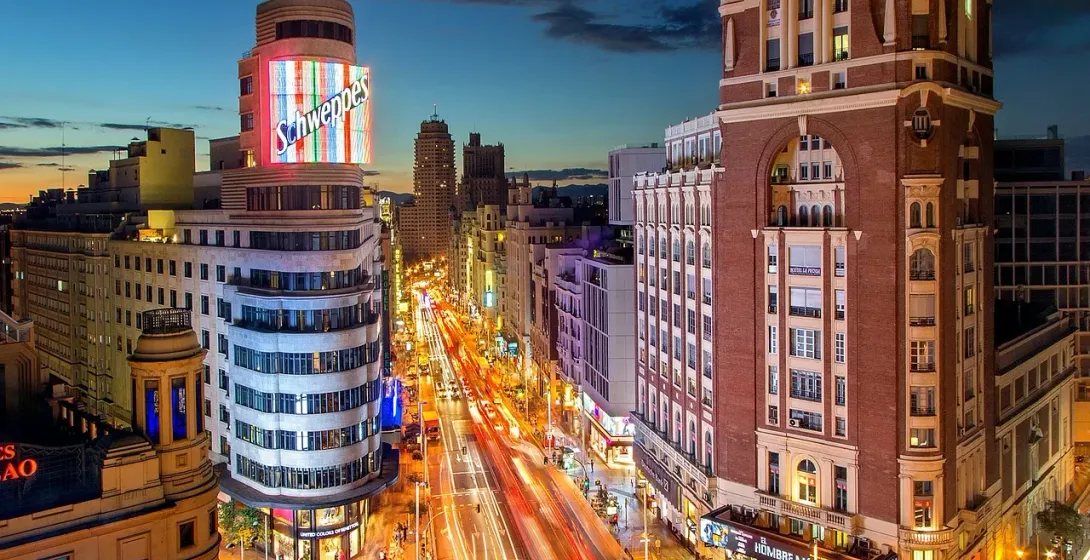 Vista nocturna de la Gran Vía de Madrid, mostrando su vibrante arquitectura y la bulliciosa vida callejera.