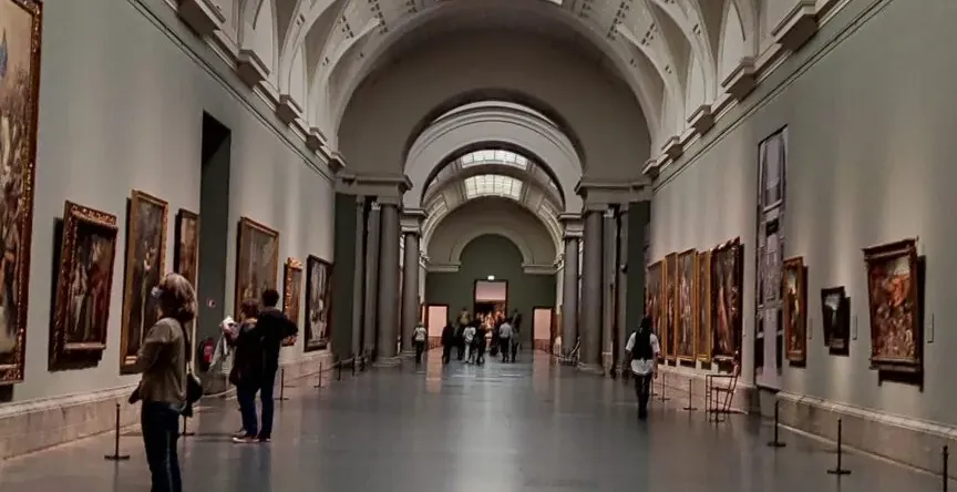 Wielka sala w muzeum sztuki z obrazami i zwiedzającymi.