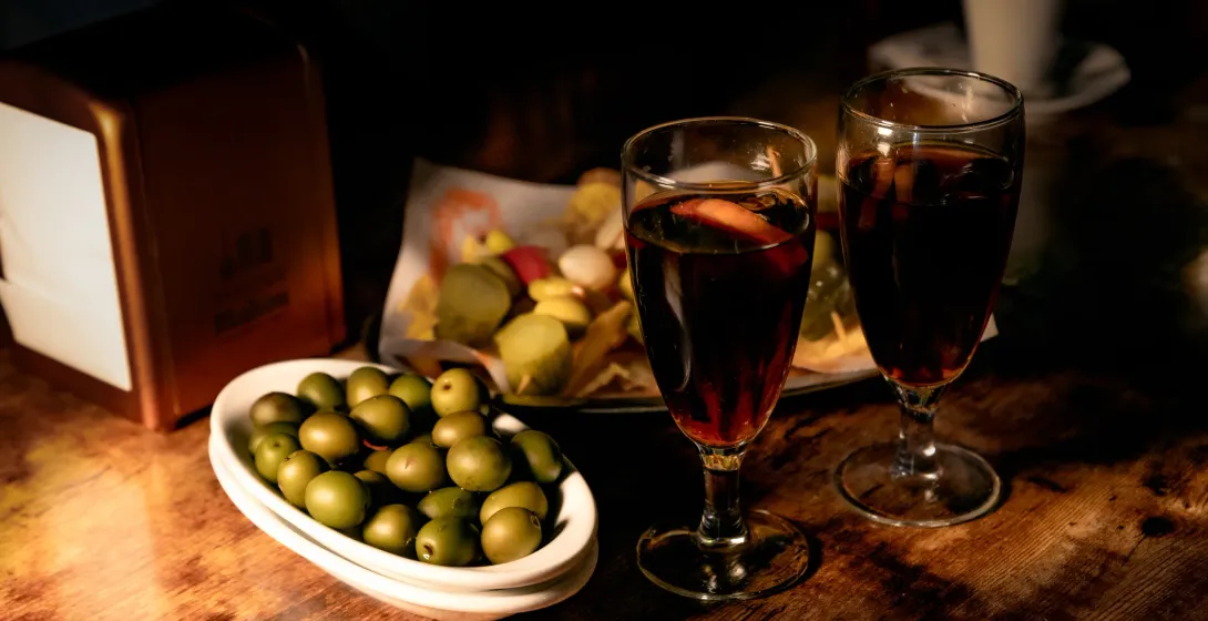 Two glasses of wine and tapas on a wooden table in a Madrid bar.