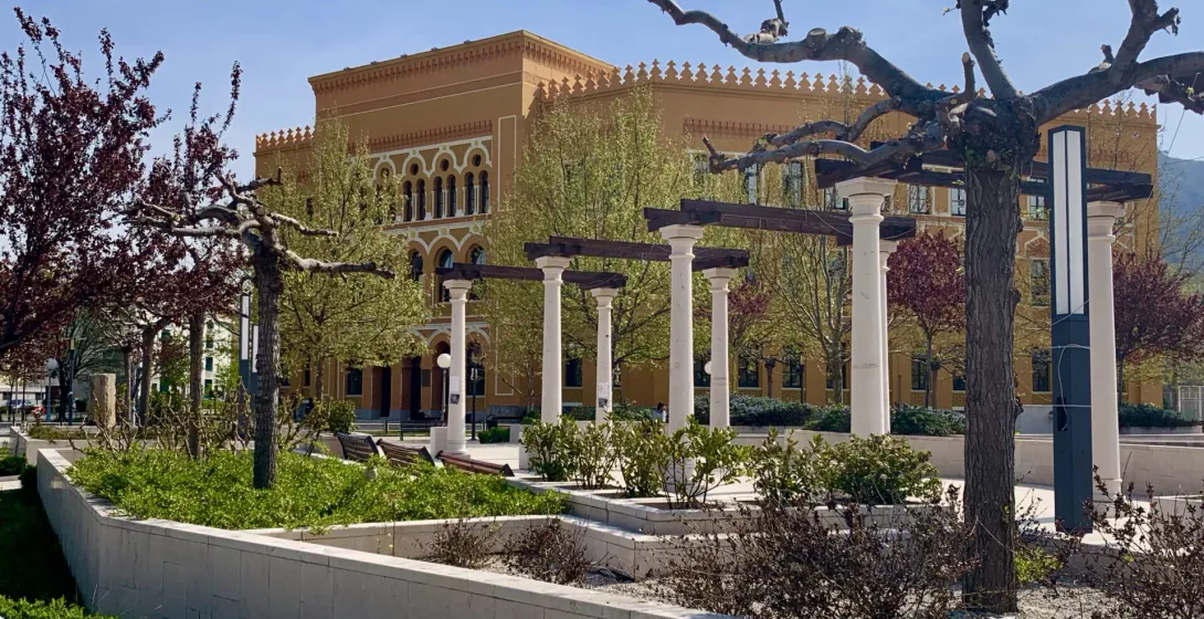 Ruhiger Park in Mostar mit einem schönen gelben Gebäude.