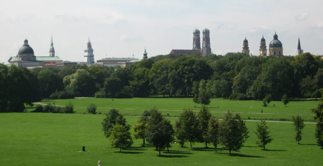 Panoramiczny widok zielonego parku w Monachium, Niemcy, z widoczną na tle panoramą miasta.