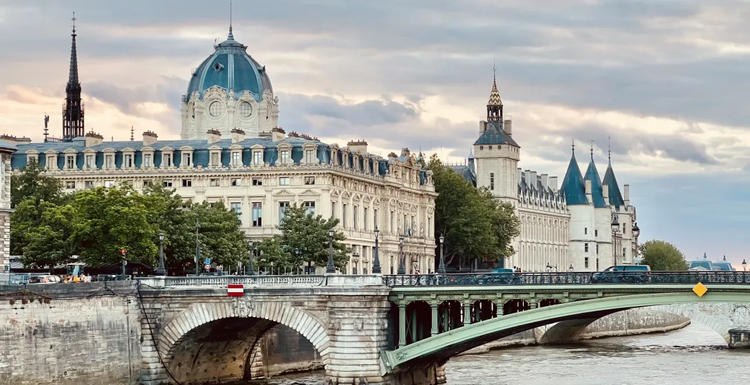 Un pintoresco puente en París, Francia, con la Conciergerie y otros edificios históricos en el fondo.