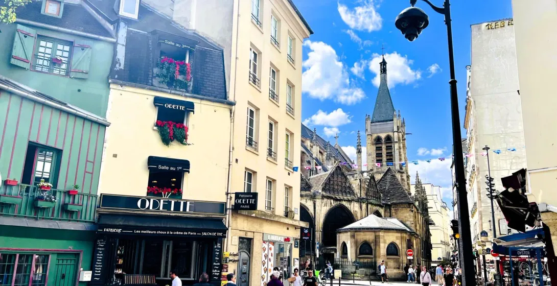 Soleada escena callejera parisina con un encantador café e iglesia histórica.