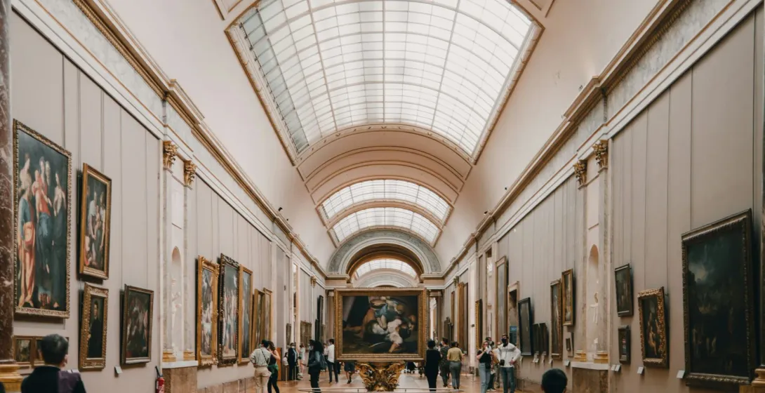 Tourists exploring a grand gallery at the Louvre Museum in Paris, surrounded by classical paintings.