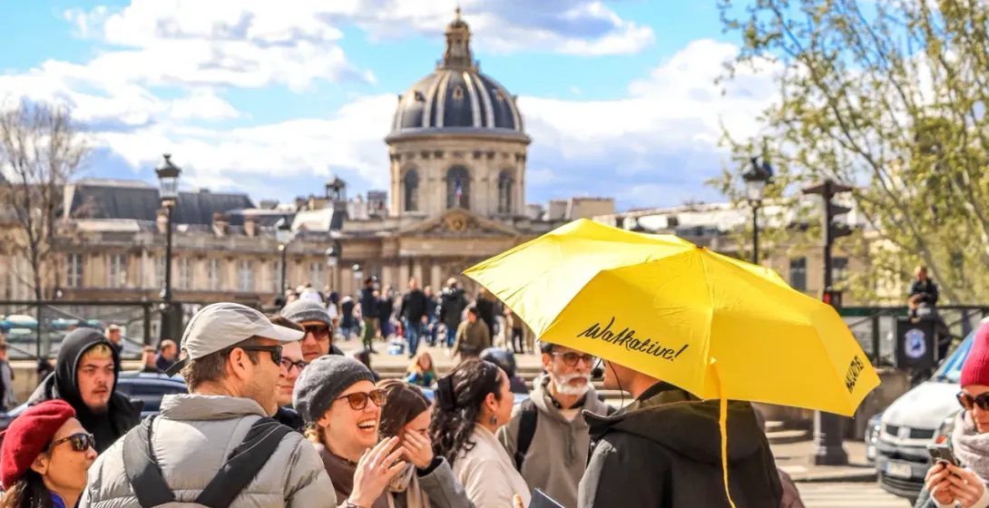 Un guía de Walkative! dirige a un grupo de turistas felices en un día soleado en París.