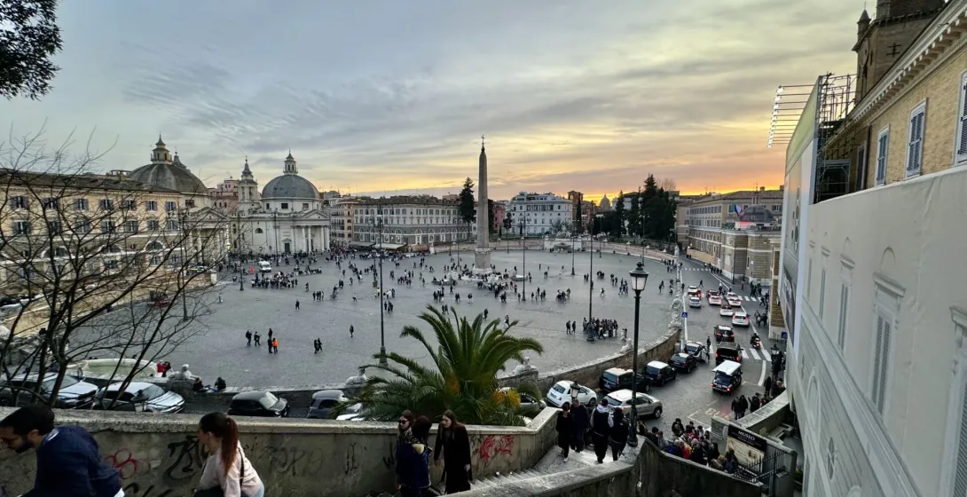 Tourists enjoying a sunset view of Piazza del Popolo in Rome, Italy.