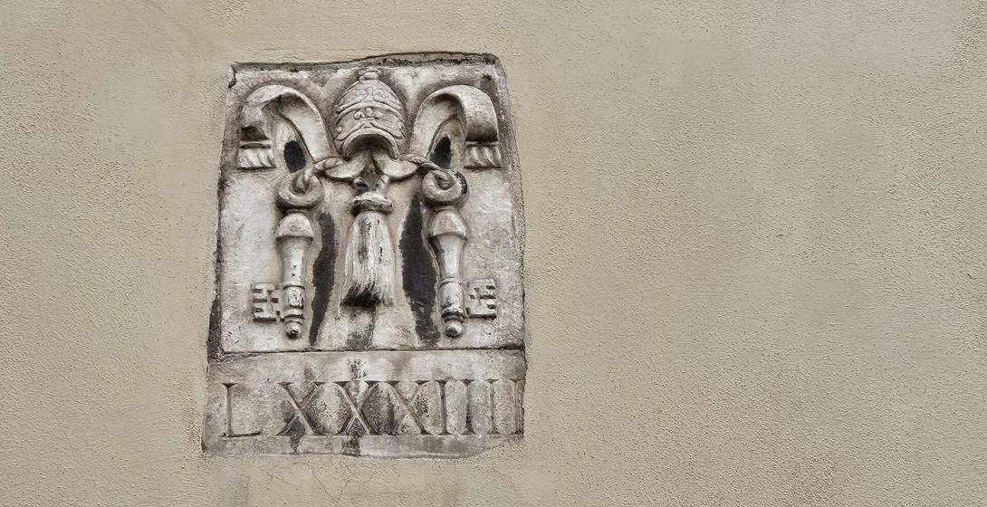 Relieve de piedra desgastado en Roma que representa la tiara papal y las llaves.